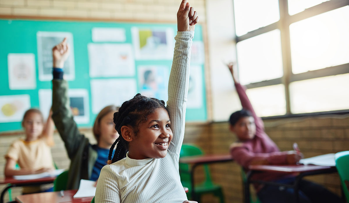 Young girl raising hand in classroom.