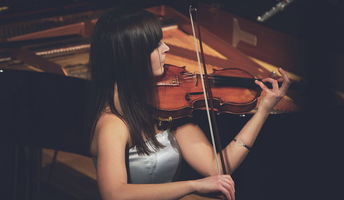 Young female concert violinist performing on stage.