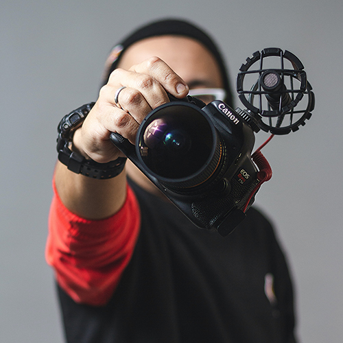man holding Canon camera in front of face